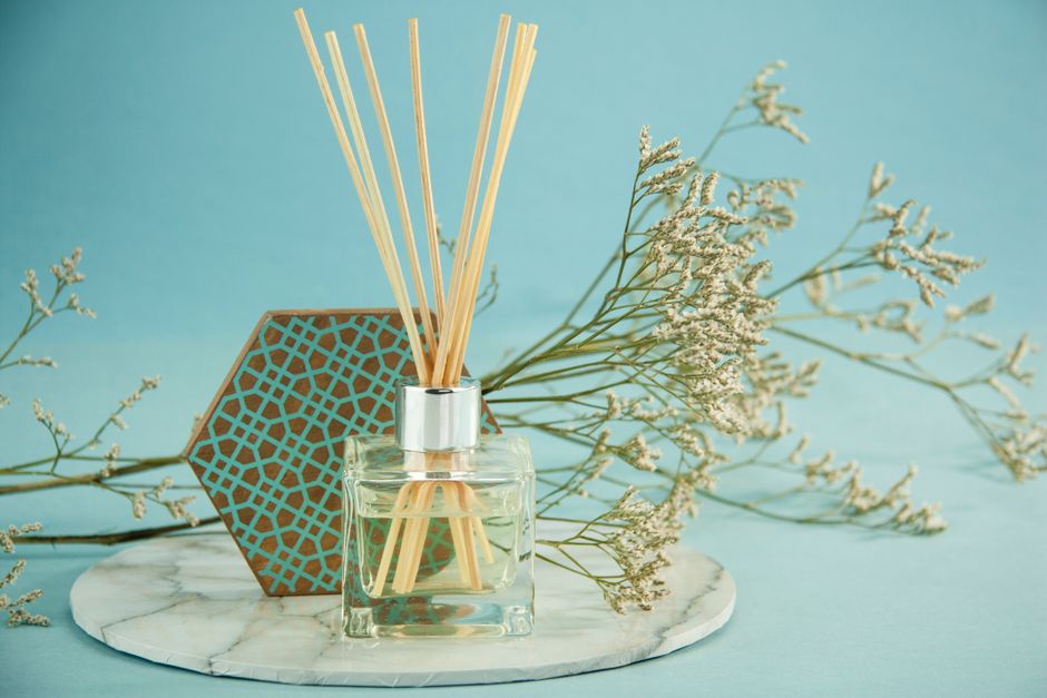 Vrouw sprayt nieuwe zomergeur in stijlvolle slaapkamer.
